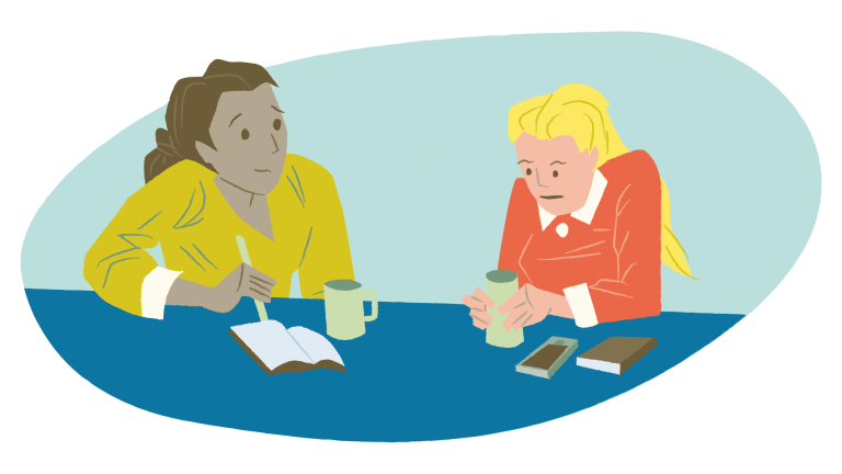 Ansatt og leder sitter ved et bord og snakker sammen. 